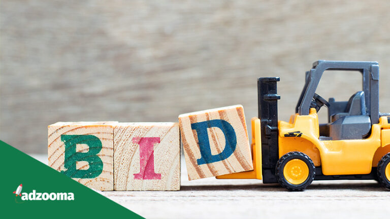 A yellow forklift pushing three wooden blocks spelling "BID"